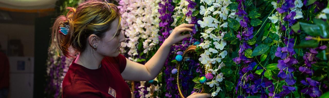 A student hanging plastic flowers on a wall